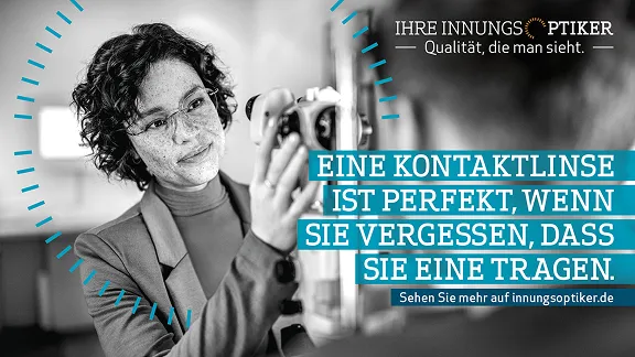 Eine junge Frau mit lockigem, dunklem Haar und Brille lächelt und hält ein optisches Gerät, während sie auf etwas außerhalb des Bildausschnitts blickt. Der Fokus liegt auf ihrem Gesicht und dem Gerät, das sie hält, was ein Gefühl von Fachwissen und Sorgfalt vermittelt. Der Text lautet: „EINE KONTAKTLINSE IST PERFEKT, WENN SIE VERGESSEN, DASS SIE EINE TRAGEN.“